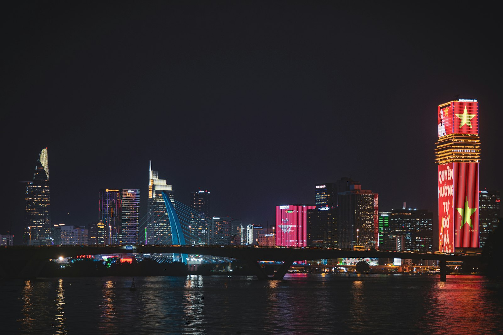 City skyline at night with illuminated buildings and bridge